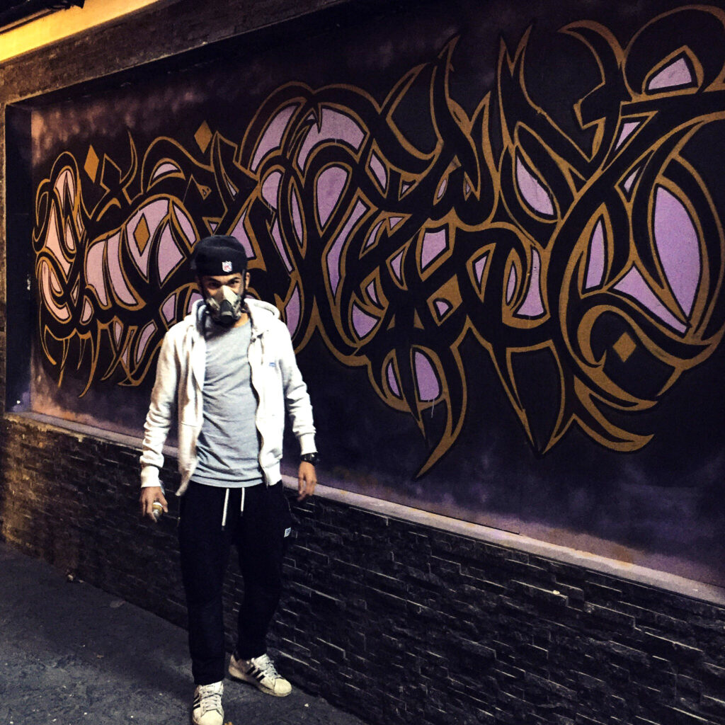 Artist in front of wall mural
